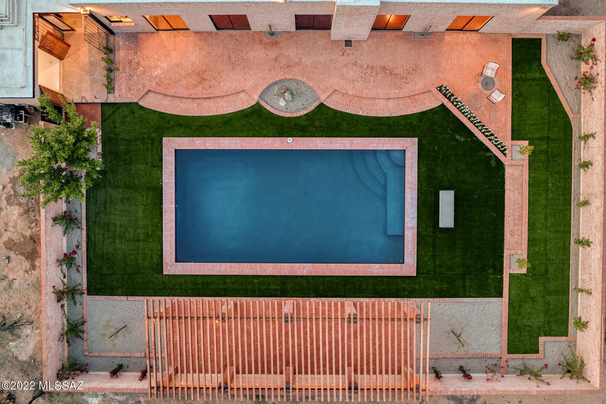 Top-down view of a pool surrounded by a patio and grass area.