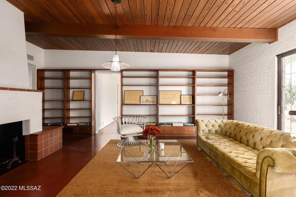 Modern living room with wooden ceiling, bookshelves, and a beige sofa.